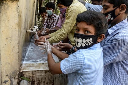 Un grupo de niños se la va las manos en un lugar público en la India