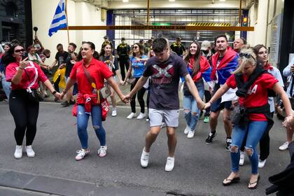 Un grupo de personas bailan y cantan afuera del hotel donde Novak Djokovic fu confinado en Melbourne, Australia, el lunes 10 de enero de 2022. (AP Foto/Mark Baker)