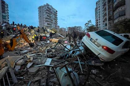 Un grupo de personas busca entre los escombros de un edificio a sobrevivientes tras un sismo, en Adana, Turquía, el lunes 6 de febrero de 2023. (AP Foto/Khalil Hamra)