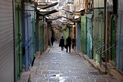 Un grupo de personas camina por una calle entre tiendas cerradas en el barrio cristiano de la Ciudad Vieja de Jerusalén, el 16 de octubre de 2023.