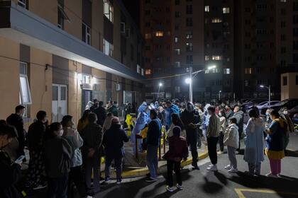 Un grupo de personas espera en fila para someterse a una prueba de detección del coronavirus en una zona residencial de Shanghai, el 10 de marzo de 2022. (AP Foto)
