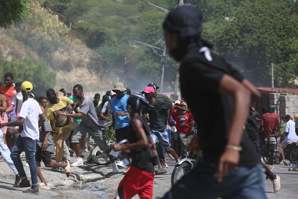 Un grupo de personas huye de los gases lacrimógenos disparados por la policía para dispersar a los manifestantes que exigían a la policía y al primer ministro medidas inmediatas contra las pandillas en Puerto Príncipe, Haití, el lunes 19 de agosto de 2024. (Foto AP/Odelyn Joseph)