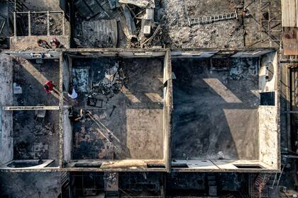 Un grupo de personas realiza labores de limpieza en medio de escombros en sus viviendas consumidas por las llamas de un incendio forestal en Viña del Mar, Chile, el lunes 5 de febrero de 2024. (AP Foto/Esteban Félix)