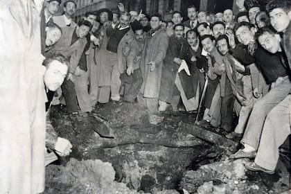 Un grupo de personas rodean uno de los cráteres que dejaron los ataques con bombas realizados por parte de la aviación naval contra el gobierno de Juan Domingo Perón