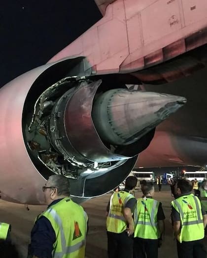 Un grupo de trabajadores de American Airlines observa el motor incendiado en el aeropuerto de Ezeiza, la noche del jueves 28 de octubre de 2022