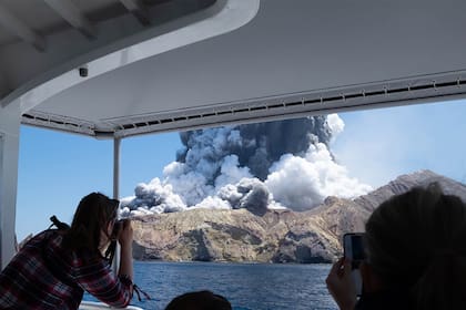 Un grupo de turistas, ayer, registra la erupción del volcán Waakari