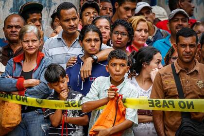 Un grupo de venezolanos observa una de las tantas escenas del crímen que son recurrentes en el país caribeño