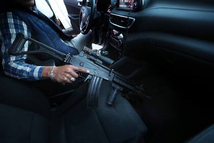 Un guardaespaldas asignado por el gobierno para proteger a Guillermo Valencia, candidato a la alcaldía de Morelia por el PRI, sostiene su fusil de asalto el sábado 22 de mayo de 2021 durante una de las escalas de campaña del candidato en esa ciudad del estado de Michoacán, México. (AP Foto/Marco Ugarte)
