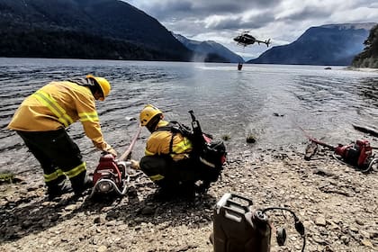 Un helicóptero con helibalde levanta agua para combatir los incendios