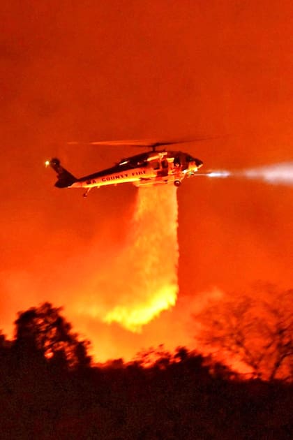 Un helicóptero Firehawk del condado de Los Ángeles arroja agua sobre las llamas durante el incendio en el Parque Nacional de Los Padres, cerca de Camino Cielo, California
