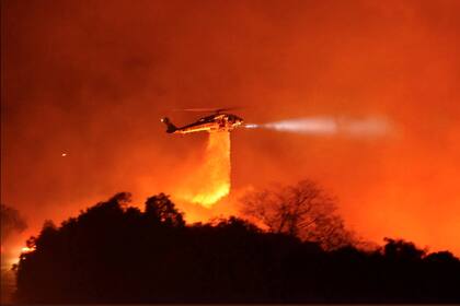 Un helicóptero Firehawk del condado de Los Ángeles arroja agua sobre las llamas durante el incendio en el Parque Nacional de Los Padres, cerca de Camino Cielo, California