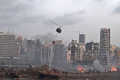 Un helicóptero intenta apagar varios incendios en la escena de la explosión masiva que golpeó el puerto de Beirut el 4 de agosto de 2020
