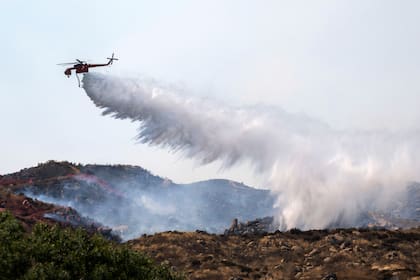 Un helicóptero trata de apagar un incendio en Reche Canyon cerca de Moreno Valley, California