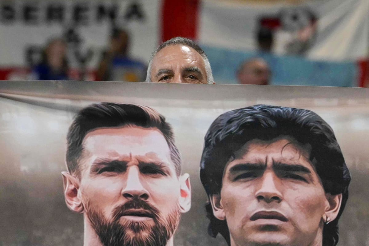 Un hincha argentino sostiene una bandera con las imágenes de Messi y Maradona, poco antes de la semifinal con Inglaterra en el último Mundial, en Atlanta