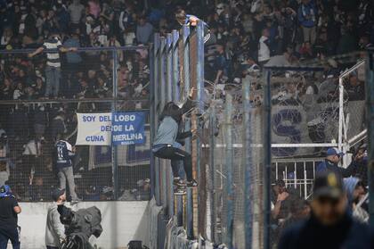 Un hincha subido al alambrado de la cancha