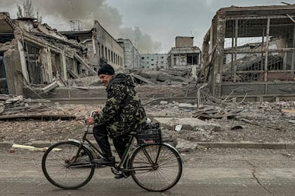 Un hombre anda en bicicleta frente a una oficina postal destruida por un ataque aéreo ruso, el 7 de noviembre de 2024, en Kurakhove, región de Donetsk, Ucrania. (AP Foto/Anton Shtuka)