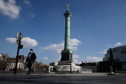 Un hombre camina con barbijo en la plaza de la Bastilla