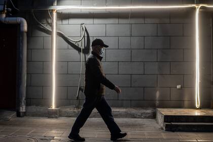 Un hombre camina con barbijo en una calle solitaria de Pekín