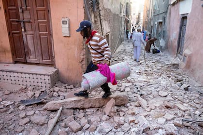 Un hombre camina con sus pertenencias entre los escombros en un callejón de la antigua ciudad de Marrakech, dañada por el terremoto, el 9 de septiembre de 2023