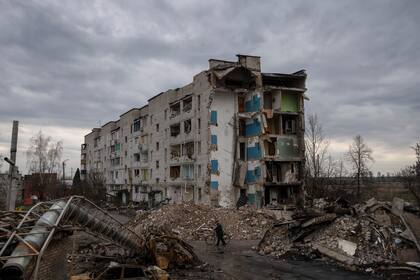Un hombre camina con una bicicleta junto a un apartamento de apartamentos destruido en la localidad de Borodyanka, Ucrania, el sábado 9 de abril de 2022. Tropas rusas ocuparon la población durante semanas. (AP Foto/Petros Giannakouris)
