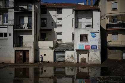 Un hombre camina en una calle inundada en Rive-de-Gier, en el centro de Francia, luego de que unas lluvias torrenciales e inundaciones sumergieron caminos y vías de tren, el viernes 18 de octubre de 2024. (AP Foto/Laurent Cipriani)