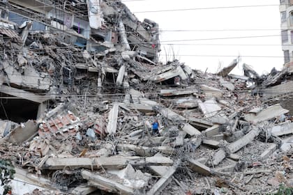 Un hombre camina entre los escombros de un edificio que se derrumbó en los terremotos del día anterior en La Guaira, Venezuela