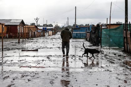 Un hombre camina por una calle fangosa en un sector pobre de Santiago el 29 de junio de 2020