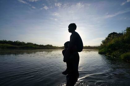 Un hombre carga a su hija al cruzar el río Bravo de Ciudad Acuña, México, a Del Río, Texas, el miércoles 22 de septiembre de 2021. (AP Foto/Fernando Llano, Archivo)
