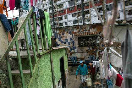Un hombre carga un balde de agua hacia su casa, en un barrio de la capital venezolana