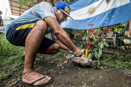 Un hombre coloca flores en la puerta de la casa donde nació Maradona en Azamor 523, Villa Fiorito