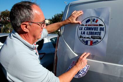 Un hombre coloca un cartel con la frase "La caravana de la libertad" en una camioneta antes de partir hacia París, en Bayona, en el suroeste de Francia, el miércoles 9 de febrero de 2022. (AP Foto/Bob Edme)