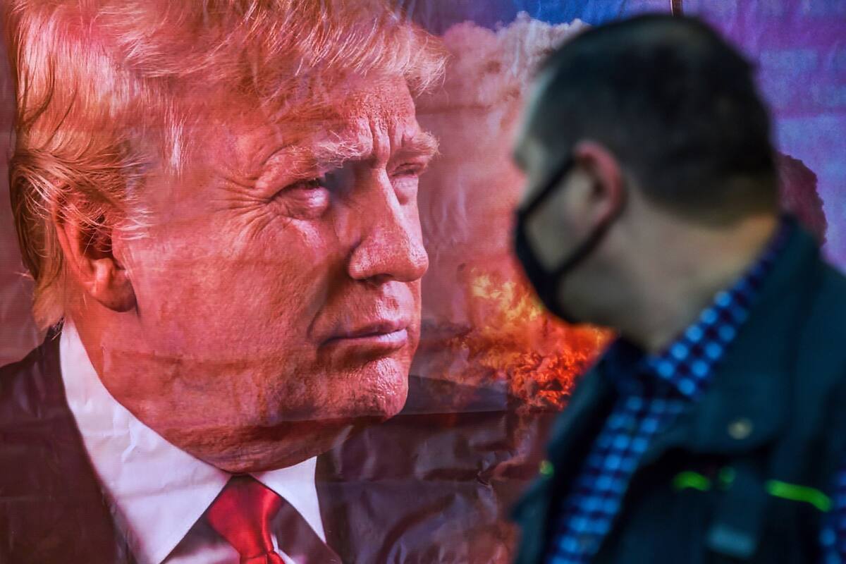 Un hombre con mascarilla pasa junto a un cartel del presidente de los Estados Unidos, Donald Trump, en Bishkek