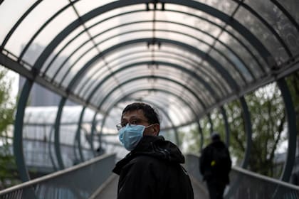Un hombre con un barbijo camina por un paso elevado en Wuhan, en la provincia central china de Hubei, donde se originó el nuevo coronavirus