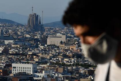 Un hombre con una máscara facial se sienta en un bar con vista a la Sagrada Familia en Barcelona el 25 de julio de 2020