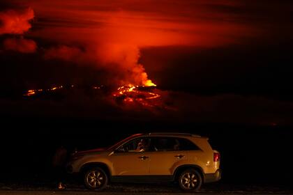 Un hombre conversa por teléfono desde su auto a lo largo de Saddle Road, la principal carretera que une las costas este y oeste de la Isla Grande de Hawai, al tiempo que el volcán Mauna Loa hace erupción el miércoles 30 de noviembre de 2022, cerca de Hilo, Hawai. (AP Foto/Gregory Bull)
