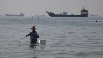 Un hombre de pie en el mar del Estrecho de Ormuz, frente a la costa de Bandar Abbas