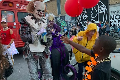 Un hombre disfrazado saluda a un niño en el desfile Krewe of Boo el sábado 23 de octubre de 2021 en Nueva Orleans. (AP foto/Rebecca Santana)