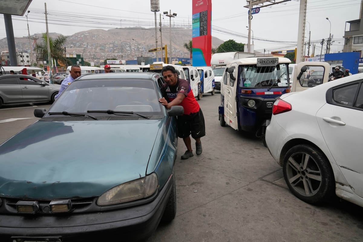 Un hombre empuja su auto en una fila de automovilistas que esperan para comprar gasolina después de que las autoridades la racionaran debido a una rotura en un gasoducto principal que afecta el suministro de gas a Lima, Perú, el miércoles 11 de marzo de 2026. (Foto AP/Martín Mejía)