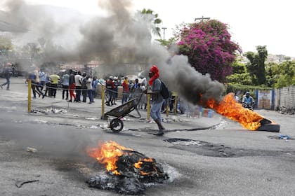 Un hombre empuja una carretilla frente a neumáticos en llamas durante una protesta para exigir la renuncia del primer ministro, Ariel Henry, el 7 de marzo, en Puerto Príncipe