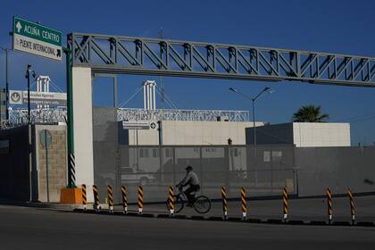 Un hombre en bicicleta frente a la entrada cerrada de un puente fronterizo internacional que conecta a las ciudades de Del Río, Texas, y Ciudad Acuña, México, el viernes 24 de septiembre de 2021. (AP Foto/Fernando Llano)