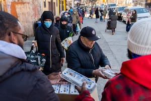 Un hombre entrega cartones de huevo a personas que esperan formadas para recibirlos de manera gratuita de parte de FarmerJawn Agriculture el viernes 21 de marzo de 2025 en el barrio de Harlem, en Nueva York