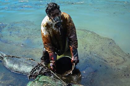 Un hombre extrae aceite derramado del buque MV Wakashio, perteneciente a una empresa japonesa pero con bandera panameña, que encalló cerca del Blue Bay Marine Park frente a la costa del sureste de Mauricio el 8 de agosto de 2020