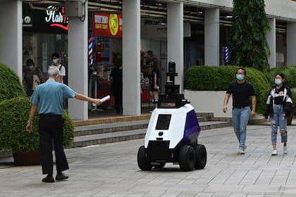 Un hombre gesticula frente al robot "Xavier" durante su patrullaje por un centro comercial de Singapur