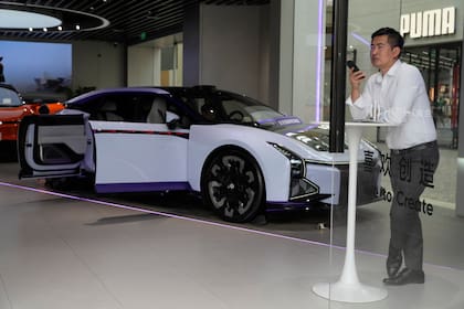 Un hombre habla por teléfono cerca de un auto eléctrico de la automotriz china HiPhi, en la sala de exhibición en Pekín, el jueves 13 de abril de 2023. (AP Foto/Ng Han Guan)