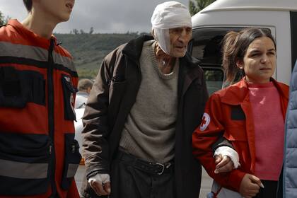 Un hombre herido de etnia armenia llamado Sasha, de 84 años, de Stepanakert, Nagorno Karabaj, es ayudado a caminar por voluntarios cuando llega a Goris, Armenia.