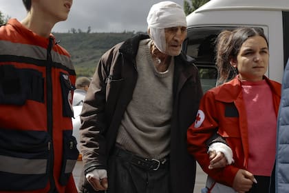 Un hombre herido de etnia armenia llamado Sasha, de 84 años, de Stepanakert, Nagorno Karabaj, es ayudado a caminar por voluntarios cuando llega a Goris, Armenia.