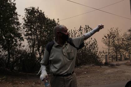 Un hombre huye de un poblado cerca de Tizi Uzu, a unos 100 kilómetros (62 millas) al este de Argel, debido a los incendios forestales en la región, el martes 10 de agosto de 2021. (AP Foto/Fateh Guidoum)
