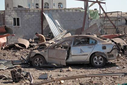 Un hombre inspecciona un auto dañado por ataques aéreos de una coalición que lidera Arabia Saudí en un taller en Saná, Yemen, el domingo 5 de diciembre de 2021. (AP Foto/Hani Mohammed)