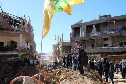 Un hombre instala una bandera de Hezbollah en un edificio dañado por ataques israelíes en Líbano