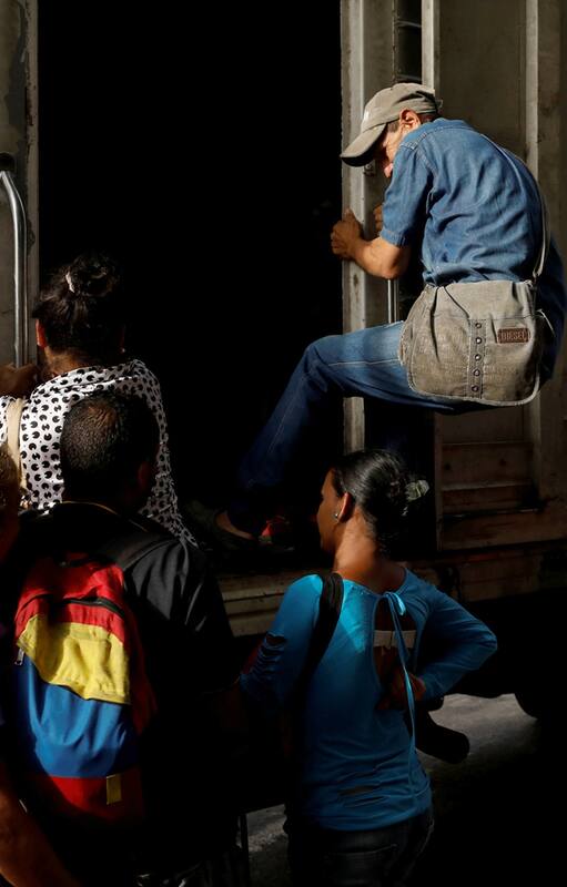 Un hombre intenta subirse a un camión de carga utilizado como transporte público